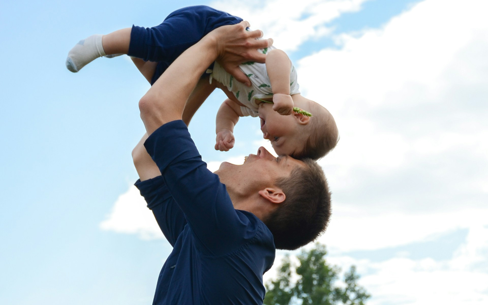 happy young man holding his baby in the air